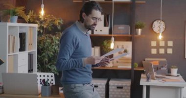 Orta Doğulu işadamının yavaş hareket eden portresi finans gazetesi okuyor sonra kameraya bakıyor ve akşam ofiste gülümsüyor. İnsanlar ve işyeri konsepti.