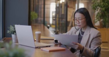 Başarılı Asyalı iş kadını gazete okuyor ve kafede kahve içiyor. Finans ve hırslı iş adamı konsepti.