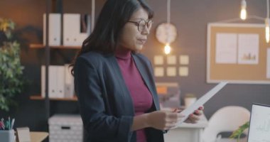 Orta Doğulu bir iş kadınının evrak okurken yavaş çekimde çekilmiş portresi. Sonra da kameraya bakıp ofiste gülümsüyor. İş ve çalışan kavramı.