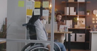 Orta Doğulu sakat bir iş kadınının tekerlekli sandalyeyi ofis masasına taşıması. Mesleki meslek ve engellilik kavramı.
