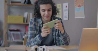 Mutlu çocuk akıllı telefonuyla video oyunu oynuyor çevrimiçi aktivitelerden ve mobil uygulamalardan zevk alıyor. Oyun ve ergenlik kavramı.