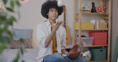 Yatak odasında beyzbol oynayan Afro-Amerikalı bir genç evde top oynayıp vakit geçiriyor. Spor ve gençlik yaşam tarzı konsepti.