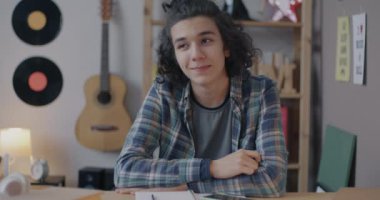 Video görüşmesi sırasında evdeki masada oturan kameraya bakan bir öğretmenin internet üzerinden konuşma ve yazma portresi. Sanal sınıf ve internet okulu konsepti.