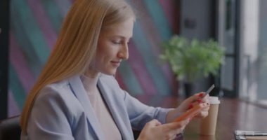 Akıllı telefon ve kredi kartı kullanan başarılı genç iş kadını kafede para transferi yapıyor. Çevrimiçi bankacılık ve iş başarısı kavramı.