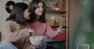 Anne ve genç kız TV seyrediyor patlamış mısır yiyor ve evde yatakta konuşuyor. Aile ilişkisi ve televizyon konsepti.