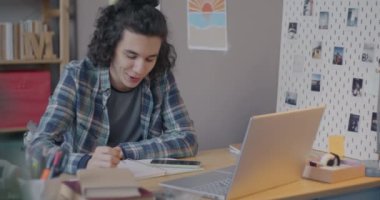 Sanal derste evde eğitime odaklanmış dizüstü bilgisayar kullanarak konuşan ve yazan neşeli melez çocuk. Uzaklık eğitimi ve modern teknoloji kavramı.