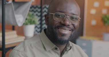 Ofisteki kameraya bakarak gülümseyen orta yaşlı Afrikalı Amerikalı girişimcinin yavaş çekim portresi. Mesleki meslek ve iş adamı konsepti.