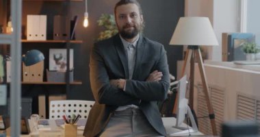 Ofis odasında kollarını kavuşturup kameraya bakan kendine güvenen iş adamının yavaş çekim portresi. İş ve kariyer kavramı.