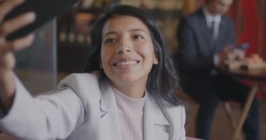 Akıllı telefon kamerasına poz veren neşeli Orta Doğulu iş kadını. Kafede öğle yemeği arasında selfie çekiyor. Fotoğraf ve modern yaşam tarzı kavramı.