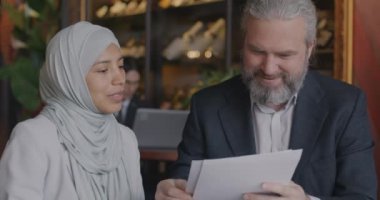 Kafkas işadamı Kafe 'deki iş toplantısı sırasında tesettürlü Orta Doğulu bir bayanla konuşuyor. İşbirliği ve profesyonel tartışma kavramı.