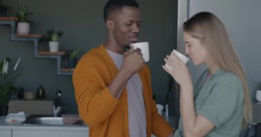 Melez bir çift çay içiyor ve mutfakta konuşuyor. İlişki ve içecek kavramı.