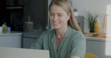 Sanal toplantıda projeyi tartışan serbest çalışan bir kadın mutfaktaki dizüstü bilgisayara bakarak konuşuyor. Çevrimiçi video çağrısı ve internet iletişimi kavramı.