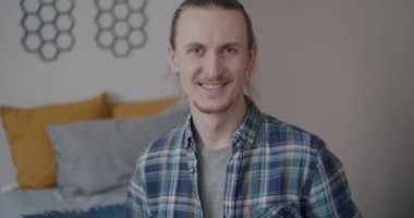 Yatak odasında, kameraya bakarak gülümseyen neşeli genç bir öğrencinin yavaş çekim portresi. Pozitif duygu ve insanların kavramı.