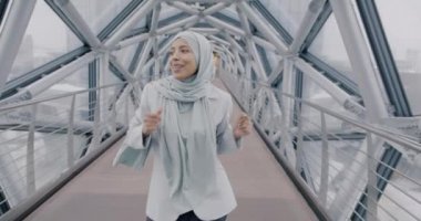 Tasasız Orta Doğulu iş kadını yaratıcı cam koridorda yürüyor iş arasında dans ediyor dinleniyor. İyi ruh hali ve gençlik kültürü kavramı.