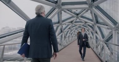 İki girişimci ofis binasının modern cam koridorunda el sıkışarak selamlaşıyorlar. İş adamları ve profesyonel iletişim kavramı.