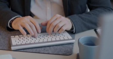 Ofis çalışanı masadaki kişisel bilgisayarı kullanırken, erkek ellerinin kablosuz klavyeyle yazışlarını yakından çek. Modern teknoloji ve iş kavramı.