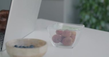 Evdeki mutfak masasında oturan Afrikalı Amerikalı bir adam dizüstü bilgisayarla yazı yazarken yakın çekim. Modern teknoloji ve serbest konsept.