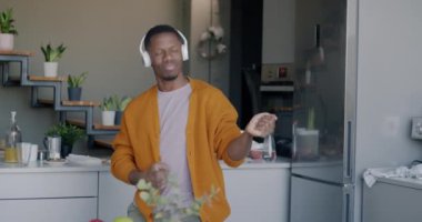 Tasasız Afrikalı Amerikalı bir adamın kulaklıkla müzik dinlemesi ve evde eğlenen hayali bir gitar çalması. Gençlik kültürü ve rahatlama etkinliği konsepti.