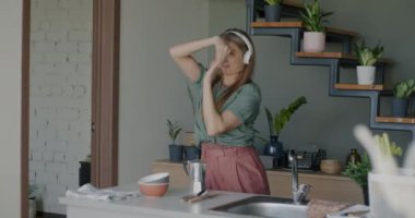Kulaklık takan, müzik dinleyen, dans eden, pop şarkılarına giden mutlu bir kız. Mutfakta eğleniyor. Milenyum kültürü ve gençlik kavramı.