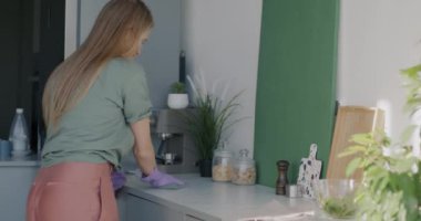 Genç bayan ev hanımı temizleme masası temizleme ve mutfakta ev işi yapma. Ev işleri ve hijyen rutin konsepti.