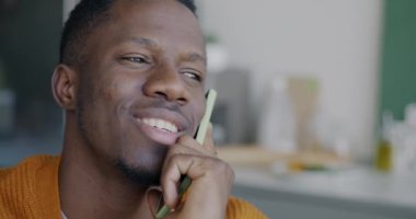 Afrika kökenli Amerikalı adamın cep telefonuyla sohbet edişinin yakın çekimi. Mutfakta cep telefonu konuşmasının keyfini çıkarıyor. Bağlantı ve iletişim kavramı.