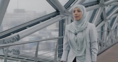 Orta Doğulu tesettürlü bir iş kadını modern cam salonda yürürken erkek meslektaşıyla tokalaşırken. Ortaklık ve iş insanları kavramı.