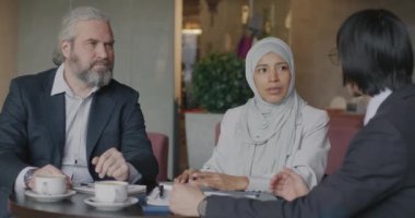 Kadın tercüman pazarlığı yaparken girişimciler kafede iş görüşmeleri sırasında konuşuyor ve tokalaşıyorlar. İş ve işbirliği kavramı.