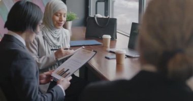 İş ortakları Orta Doğulu kadın ve Asyalı erkek kafedeki buluşmada projeyi tartışan ve not defterine yazan fikirleri paylaşıyorlar. İşbirliği ve takım çalışması kavramı.
