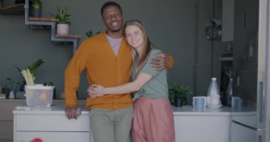 Neşeli genç insanların zoom portresi. Mutfakta dikilip kameraya bakan çift ırklı erkek ve kadın. İlişki ve aile kavramı.