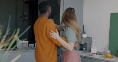 Oyuncu beyaz kadın ve Afrikalı Amerikalı erkek mutfakta el ele dans edip boş zamanlarında eğleniyorlar. Romantik ilişki ve neşeli insanlar konsepti.