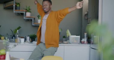 Neşeli Afrikalı Amerikalı adam dans ediyor müziğin keyfini çıkarıyor modern evde mutfakta eğleniyor. Boş zaman aktivitesi ve neşeli insan konsepti.