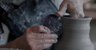 Çömlek atölyesinde vazo yapımında kullanılan aletlerle çalışan erkek ellerinin yakın çekimi. Seramik ve mesleki işgal kavramı.