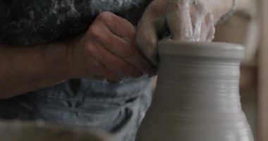 Profesyonel çömlekçilerin yakın çekimi dönen çarkın üzerinde vazo kalıbı döşeyerek eşsiz sanat eserleri yaratıyor. Meslek ve üretim kavramı.