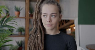 Rastalı genç bir kadının portresi. Evin içinde kameraya bakıyor. Halk ve iç mekan kavramı.