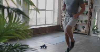 Ortadoğulu genç bir sporcu evde kulaklıkla müzik dinleyip antrenman yapıyor. Sağlık ve spor konsepti.