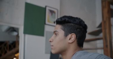 Evde spor yaparken kaslarını çalıştıran motive olmuş Orta Doğulu bir adamın eğik portresi. İnsanlar ve aktif yaşam tarzı kavramı.