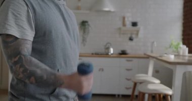 Ağırlıkla antreman yapan ve evde kablosuz kulaklıkla müzik dinleyen kaslı bir adam. Spor ve vücut geliştirme konsepti.