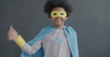 Gri arka planda kameraya bakıp gülümseyen Afro-Amerikan çocuk portresi. Mutluluk ve memnuniyet kavramı.