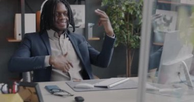 Yaratıcı Afrikalı Amerikalı adam, iş molasında ofis odasında müzik dinleyip eğleniyor. Modern teknoloji ve oyuncu kişi konsepti.