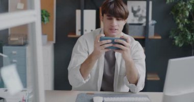 Neşeli Ortadoğulu adam, ofiste çalışırken cep telefonu uygulaması kullanarak online video oyunu oynuyor. Oyun ve iş adamı konsepti.