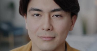 Kameraya bakan Asyalı adamın yakın plan portresi bulanık evin arka planına karşı ciddi bir yüz ifadesiyle. İnsanlar ve duygu kavramı.