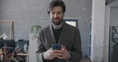 Ofis çalışanının iş yerinde yürüdüğü ve internet iletişimine odaklanmış akıllı telefonu kullandığı Dolly 'nin fotoğrafı. Mobil teknoloji ve iş adamı kavramı.