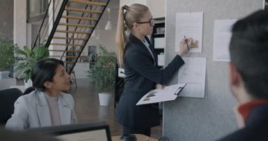 Kendine güvenen bir iş kadını iş toplantısı sırasında bilgi açıklayan bir grup insanla konuşuyor. Liderlik ve şirket yönetimi kavramı.