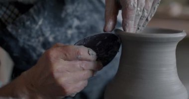 Yaratıcı vazonun yakın plan çekimleri çömlek çarkında dönerken sanatçı da kilden toprak eşyalar yapıyor. Geleneksel üretim ve küçük işletme kavramı.