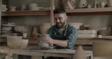 Kirli önlüklü bir gencin atölyede çömlekçiliğin keyfini çıkarması. Yaratıcı etkinlik ve olumlu duygu kavramı.