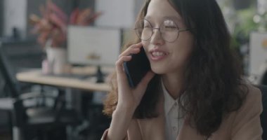 Genç Asyalı kadın cep telefonuyla konuşuyor iş konuşmaları profesyonel iletişime odaklandı. İş ve cep telefonu bağlantısı kavramı.
