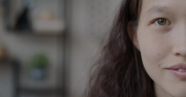 Genç Asyalı yarı yüzlü bir kadının yakın plan portresi bulanık arka planda gülümseyen kameraya bakıyor. İnsanlar ve iyi ruh hali kavramı.