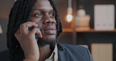 Cep telefonuyla konuşan Afro-Amerikalı işadamı ofiste profesyonel sohbetin tadını çıkarıyor. İletişim ve iş insanları kavramı.