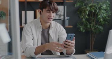 Orta Doğulu bir ofis çalışanı, ofisindeki masada oturan kulaklıkları ve akıllı telefonları kullanarak çevrimiçi video görüşmesi yapıyor. Sanal iletişim ve iş insanları kavramı.