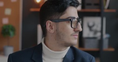 Orta Doğulu iş adamının yavaş çekim portresi modern ofiste gülümseyen kameraya dönüyor. İş ve insan kavramı.